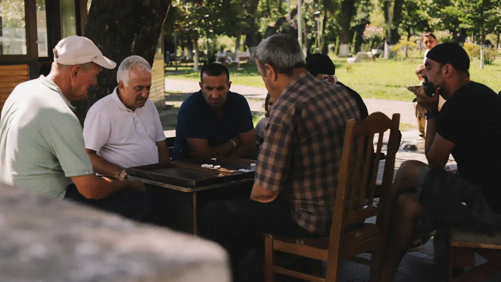 Older men playing backgammon together in a park